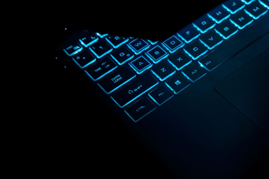 Cyan backlit laptop keyboard keys in the dark