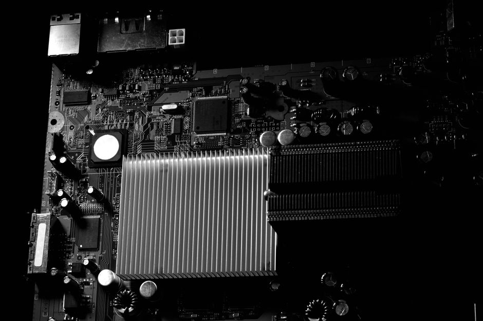 Finned motherboard heatsink on a dark circuit board in monochrome